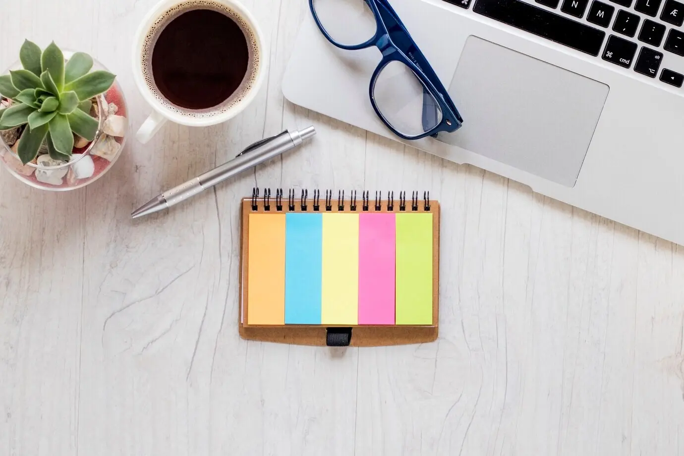 A colorful notepad next to coffee and a notepad.
